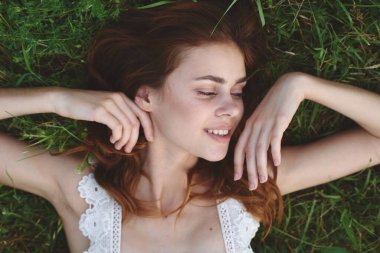 Genç bir kadın çimlerin üzerinde yatıyor. Üst görünüm