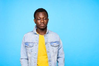 Stüdyoda poz veren yakışıklı genç adam mavi arka planda izole edilmiş.