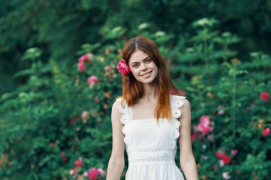 Bahçesinde gül çiçeği olan genç bir kadın