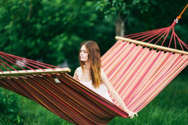 Genç ve güzel bir kadın hamakta dinleniyor.