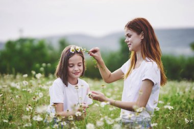 Genç anne ve kızı papatya tarlasında eğleniyorlar.