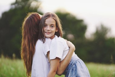 Genç anne ve kızı papatya tarlasında eğleniyorlar.