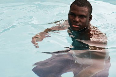 Havuzda poz veren genç yakışıklı adam.