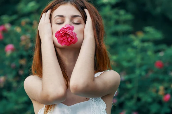 Young woman with rose flower in the garden