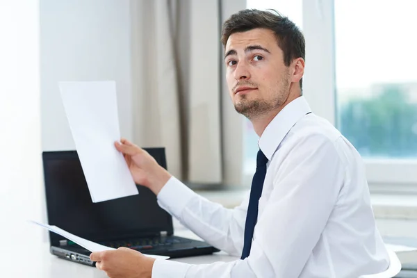事務所にノートパソコンと書類を持つ若いビジネスマン — ストック写真