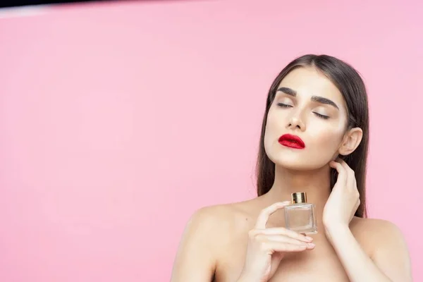 Portrait of young beautiful  woman with perfume bottle. Studio shot