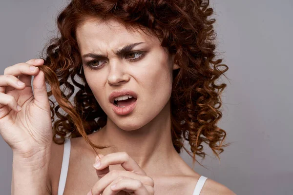 Portrait of young beautiful unhappy woman with curly hair. Studio shot