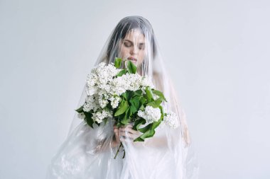 Plastik çarşafın altında elinde çiçekler olan genç bir kadın. Ekoloji kavramı