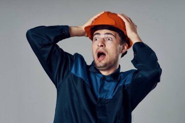 Stüdyo çekimi. Turuncu kasklı genç işçi korkuyor. 