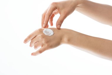   Genç ve güzel bir kadın izole edilmiş arka planda stüdyoya el kremi sürüyor.          