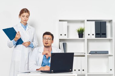 Bilgisayarlı genç doktor ve hastane ofisinde hemşire. 