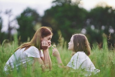 Genç anne ve kızı papatya tarlasında eğleniyorlar.