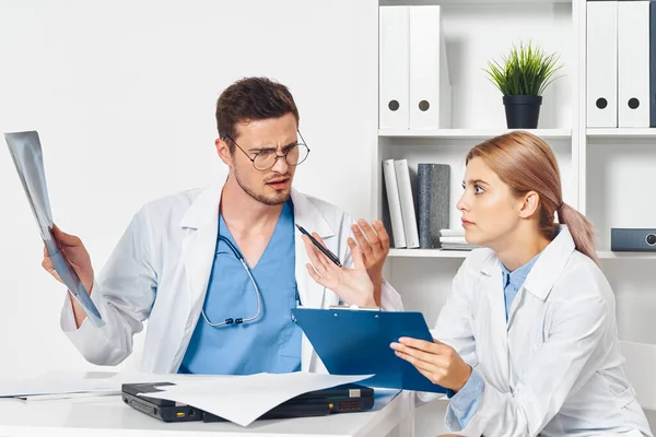 Young doctor and nurse in hospital looking at clip board