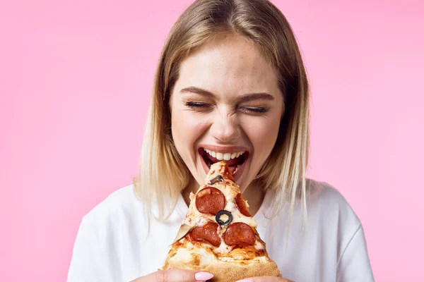 Женщина ест нездоровую пищу на цветном фоне модели — стоковое фото