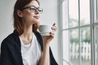 Güzel bir kadın pencere kenarındaki duygu modelinden içer.