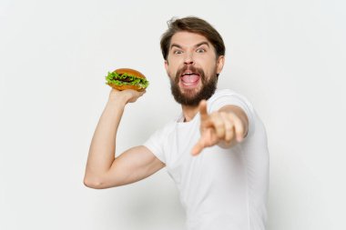 Bir hamburgeri izole bir arka plan saldırganlığına açık ağıza fırlatır.