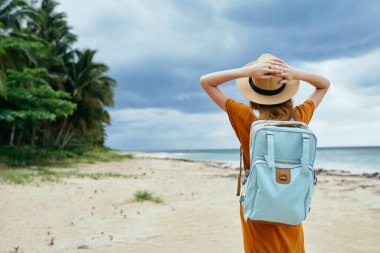 Güzel kadın turist sırt çantası beyaz kumlarda yürür