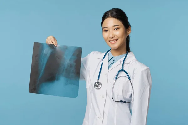 Žena lékař v lékařském kabátě drží rentgen v její ruce úsměv — Stock fotografie