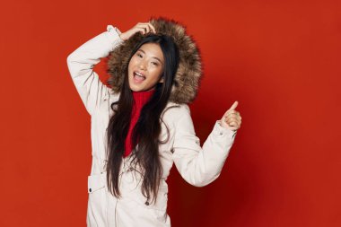 Güzel kadın sıcak kıyafetler kaput modeli kırmızı arka plan gülümsemesi 