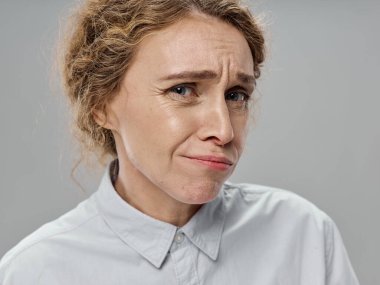 Kadın, izole edilmiş bir arka planda kameraya şaşkınlıkla bakıyor.