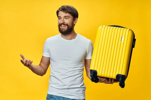 Muž v tričku a džínách se žlutým kufříkem v rukou se směje — Stock fotografie