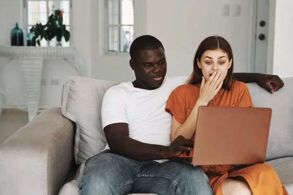 Un homme heureux d'apparence africaine regarde un ordinateur portable et une femme admirative — Photo