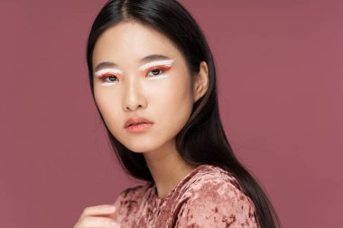 Alışılmadık makyajı ve ipek elbisesi olan kendine güvenen bir kadın.