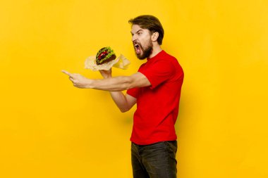 Elinde hamburgerle agresif bir adam parmağını gösteriyor. 