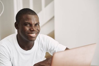 Afrika görünümlü, gülümseyen ve dizüstü bilgisayarı olan mutlu bir adam..