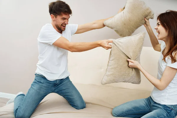 Una mujer y un hombre pelean almohadas en el sofá — Foto de Stock