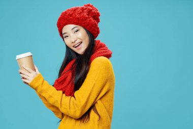 Örgü şapkalı mutlu kadın elinde bir fincan kahve tutuyor. 