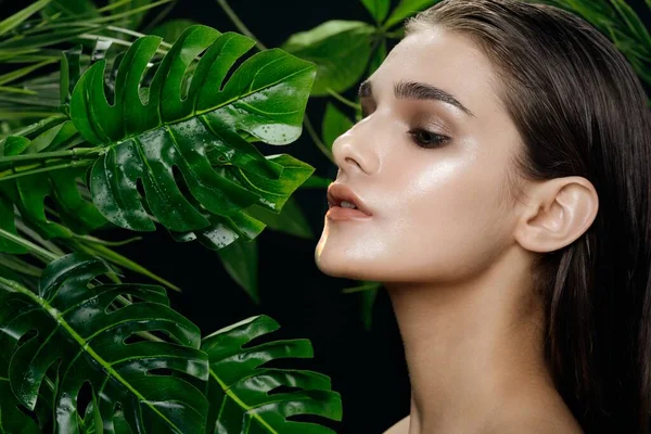 Una mujer con la piel limpia se para cerca de hojas verdes — Foto de Stock