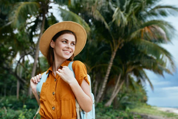 En lycklig kvinna tittar på naturen med en ryggsäck på ryggen — Stockfoto