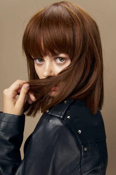 Jovem bela mulher posando em um fundo bege no estúdio em uma jaqueta de couro preto — Fotografia de Stock