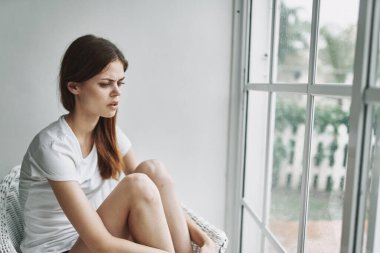 Pencere kenarında oturan üzgün kadın.