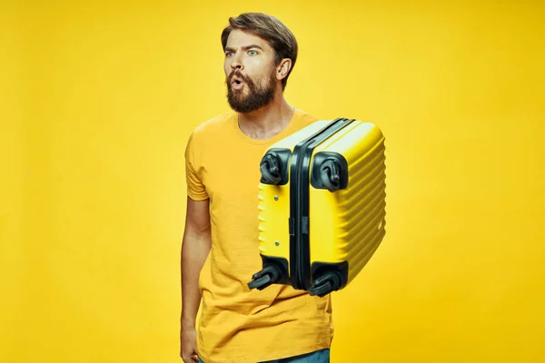 An indignant man holds a yellow suitcase in his hand — Stock Photo, Image