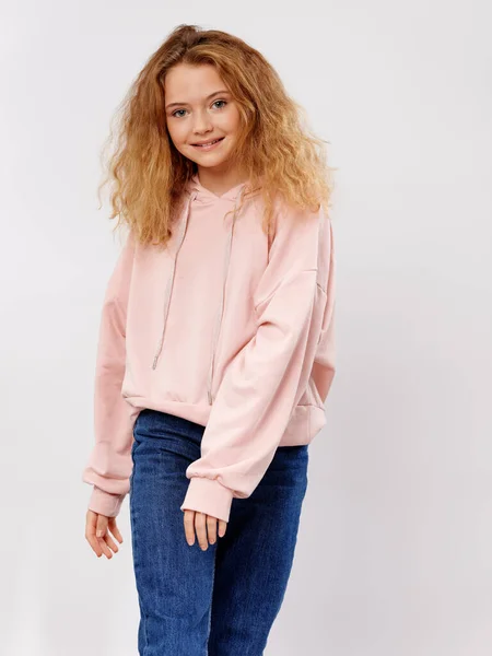 Gelukkig meisje in een roze trui en jeans glimlacht — Stockfoto