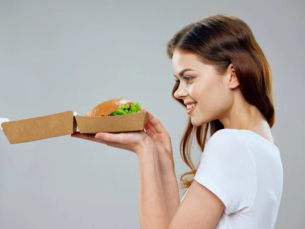 Happy woman onderzoekt een hamburger in een kartonnen doos — Stockfoto