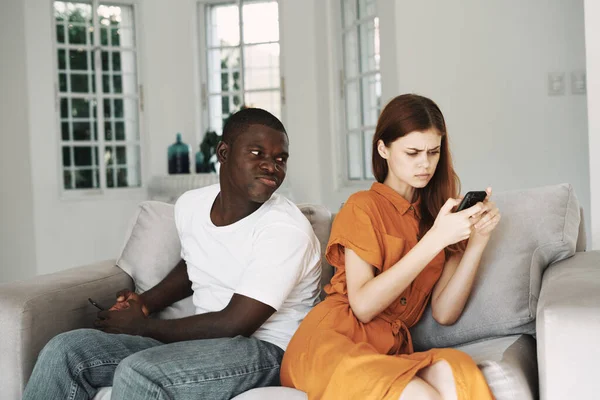 Uma mulher examina um telefone celular e um homem de aparência africana — Fotografia de Stock