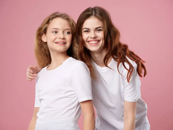 Schöne Frau und kleines Mädchen steigen auf einem rosa Hintergrund Familie — Stockfoto