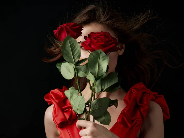 Mulher encantadora com rosas vermelhas em um fundo preto — Fotografia de Stock