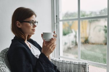 Bardakta sıcak içecekle gözlüklü güzel bir kadın. 