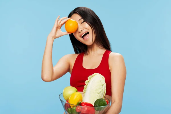 Schöne Frau in einem roten Tanktop mit frischem Gemüse und Obst — Stockfoto