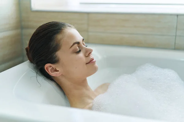 Die Frau badet in einer Badewanne mit weißem Schaum — Stockfoto