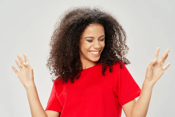 Gelukkig vrouw in rood t-shirt gesticulating met handen en krullend haar — Stockfoto