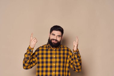  Ekose gömlekli sakallı adam elleriyle el kol hareketi yapıyor.
