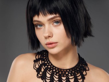 Boynunda süslemesi olan siyah peruklu bir kadın.