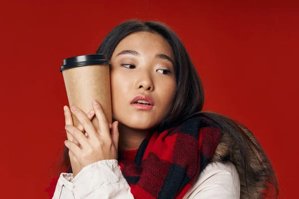 Gyönyörű nő, piros háttérrel, ölelget egy csésze kávét. — Stock Fotó