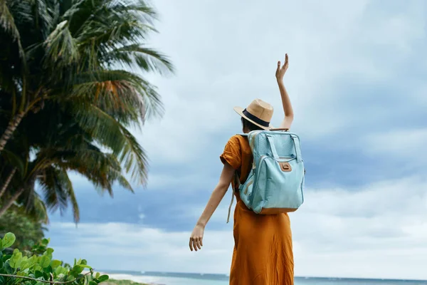 Mulher com a mão levantada no oceano com uma mochila — Fotografia de Stock