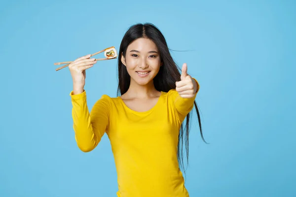 Счастливая женщина показывает позитивный жест, держа в руках суши-роллы. — стоковое фото